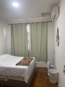 een slaapkamer met een bed en een raam met gordijnen bij Apartamento na Pituba in Salvador
