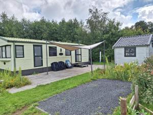 DiepenheimStacaravan Diepenheim的院子里有一栋带露台的绿色小房子。