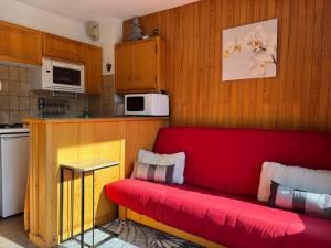 a red couch sitting in a kitchen with a kitchen gmaxwell gmaxwell gmaxwell gmaxwell gmaxwell gmaxwell at Appartement Chez Jean - 2 chambres - Centre du Village - À 30 mètres des télécabines in Champagny-en-Vanoise