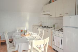a kitchen with a white table and a white refrigerator at Zeljana in Metajna
