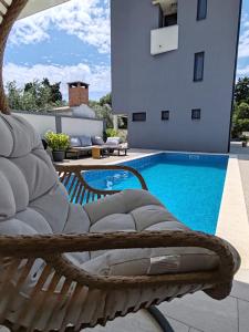 a wicker chair sitting next to a swimming pool at Villa Ivano in Petrcane