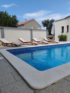 a swimming pool with lounge chairs next to a building at Villa Ivano in Petrcane