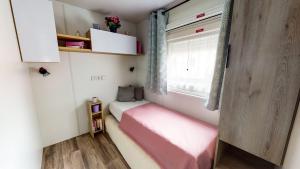 波讷地区圣朱利安Chez Bruno & Sophie Mobil home luxe 6-8P BORA BORA的一间小卧室,配有粉红色的床和窗户