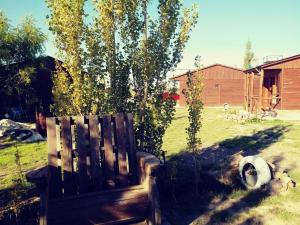 a wooden bench in a yard next to a tree at Cabañas don fortuno in Puerto Deseado