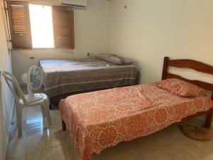 a room with two beds and a chair and a window at Casa de Praia - Coqueiro - Piauí in Luis Correia +30 photos