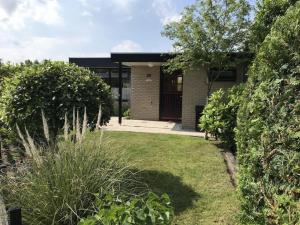 a brick house with a garden in front of it at Bungalow in Wildrijk with Fenced Garden in Sint Maartenszee
