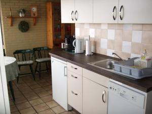 a kitchen with white cabinets and a sink at Bungalow in Wildrijk with Fenced Garden in Sint Maartenszee +17 photos