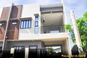 a large white house with a fence in front of it at Palazzo Olympu Guest House in Bantay