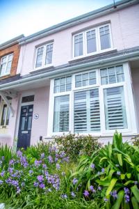 a pink house with white windows and purple flowers at Stylish Padstow Townhouse in Padstow +38 photos