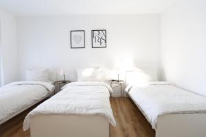two beds in a room with white walls at Apartment "Paris" in Erftstadt - 3 Zimmer & 77qm - nahe Köln, Messe, Phantasialand & Bonn - Familienurlaub oder Business Trip in Erftstadt