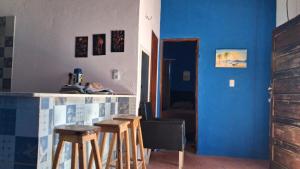 a kitchen with blue walls and a bar with stools at Chalé marlin azul in Icapuí
