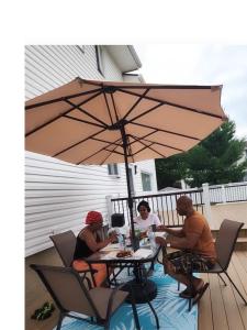 three people sitting at a table under an umbrella at Baldwin, NY 1 Bedroom Apartment Queen Size Bed in Baldwin +23 photos