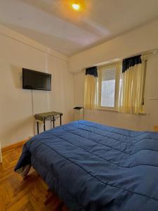 una camera da letto con un letto blu e una televisione di Departamento de dos ambientes en plaza Colon a Mar del Plata