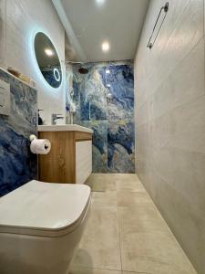 a bathroom with a toilet and a blue wall at Best Family Apartment in Varna City