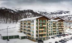 ein großes Gebäude mit auf einem Parkplatz geparkten Autos in der Unterkunft Crystal Residence Bakuriani in Bakuriani