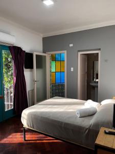 a bedroom with a large bed and a colorful window at Sin Fin Hostel in Mendoza +87 photos