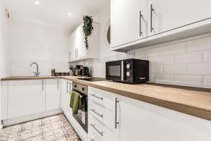 La cuisine est équipée de placards blancs et d'un four micro-ondes noir. dans l'établissement Stylish Apartment in Coventry Center With Free Parking, à Parkside 28 autres photos