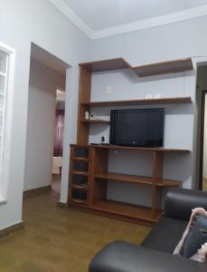 Una sala de estar con un televisor de pantalla plana en un centro de entretenimiento. en Edifício Patinhas, en Marataízes