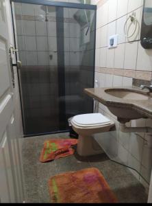 Un baño con inodoro, lavabo y ducha. en Edifício Patinhas, en Marataízes