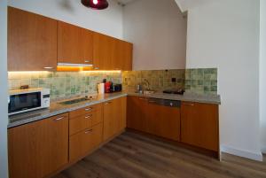a kitchen with wooden cabinets and a microwave at SnowGranada Parking telecabina Pradollano Include in Sierra Nevada