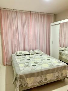 a bedroom with a large bed with pink curtains at Aconchegante casa em Marataizes in Marataizes