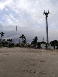 a beach with a cell phone tower and palm trees at kitnet family - 2 quadras da praia da Enseada in Guarujá
