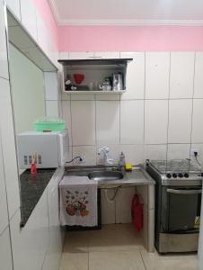 a small kitchen with a sink and a stove at kitnet family - 2 quadras da praia da Enseada in Guarujá