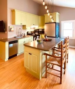 a kitchen with yellow cabinets and a kitchen island with chairs at KingstonStays The Neighbourhood, Expansive loft, free parking in Kingston