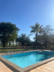 a swimming pool with palm trees in the background at Chalé Rancho Ouro Verde in Rolândia +17 photos
