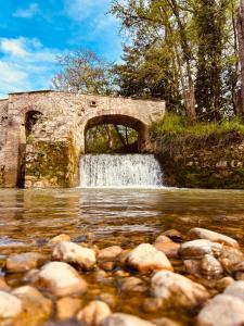 a stone bridge over a river with a waterfall at Le Moulin de Toquedonnes Gîte insolite in Saint-Michel