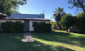 a white house with a yard with a driveway at Longreach Caravan and Cabin Park in Longreach