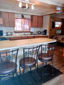 a kitchen with a counter with three chairs around it at Lakeshore Motel Ice Lake in Iron River