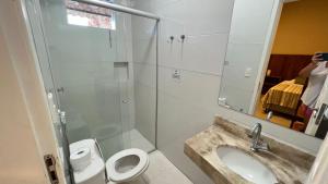 a bathroom with a sink and a toilet and a shower at Suítes Curió - Passarim Hospedagem in Cumuruxatiba