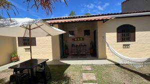 a table and an umbrella in front of a house at Suítes Curió - Passarim Hospedagem in Cumuruxatiba