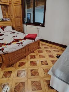 a bedroom with a bed and a wooden floor at Casa de vacanta in Târgu Jiu