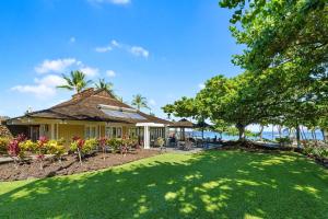 a house with a lawn and trees and the ocean at 1805 Kulalani in Waikoloa