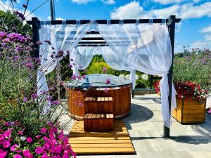 a gazebo with a tub in a garden with flowers at Gackowo in Ostróda
