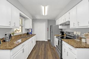 a kitchen with white cabinets and wooden floors at Cozy Villa with Spacious Outdoor Space in Orange City