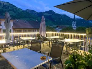 un patio con tavoli e ombrelloni con montagne sullo sfondo di Auberge de l'Ange ad Albeuve