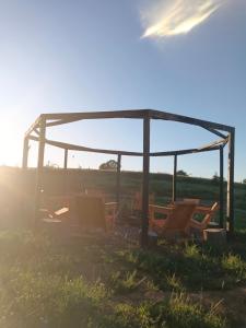 a group of chairs sitting under a gazebo in a field at casa rural el saltillo in Pemuco