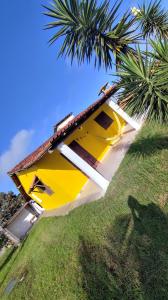 une maison jaune avec un palmier devant dans l'établissement Recanto Bougainville, à Angelim