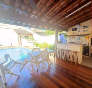 a patio with a table and chairs next to a pool at House in Bertioga - Indaia in Bertioga