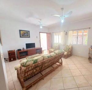 a living room with a couch and a tv at House in Bertioga - Indaia in Bertioga