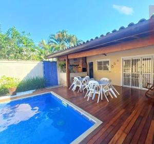 a deck with a pool and chairs and a house at House in Bertioga - Indaia in Bertioga