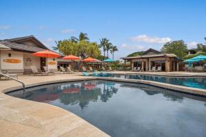 a swimming pool with chairs and umbrellas in a resort at 518 Villages at Mauna Lani in Waikoloa