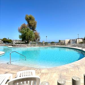 a large swimming pool with two white chairs in it at Departamento en La Herradura in Coquimbo