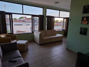 a living room with a couch and chairs and windows at Quarto Domiciliar em Antares Maceió in Maceió