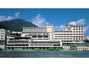a large white building with a mountain in the background at Gero Onsen Ogawaya - Vacation STAY 83607v in Gero