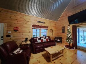 a living room with leather furniture and a christmas tree at Hocking Hills Cabin, Hot Tub, Private Pond in Stella