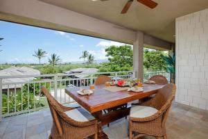 a wooden table and chairs on a patio with a balcony at 622 Villages at Mauna Lani in Waikoloa